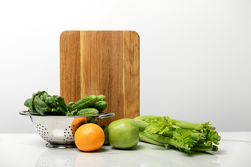 tasty and sweet fruits near ripe, fresh vegetables and wooden cutting board on grey