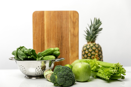 selective focus of broccoli near ripe fruits and fresh green vegetables on white