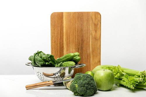 green broccoli near ripe apple and fresh vegetables on white