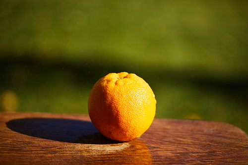 selective focus of whole and ripe orange on wooden cutting board