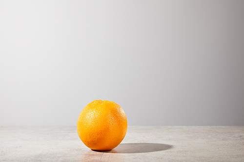 whole and ripe orange on grey background with copy space
