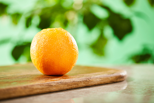 selective focus of whole orange on wooden cutting board