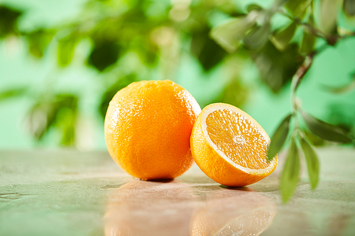 selective focus of cut and whole oranges on marble surface