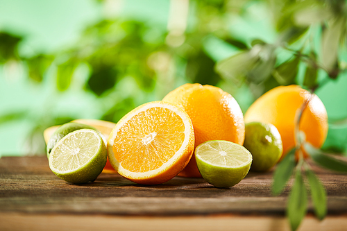 selective focus of cut, whole oranges and limes on wooden surface
