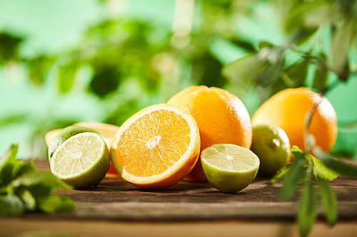 selective focus of cut, whole oranges and limes on wooden surface