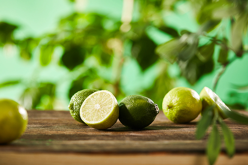 selective focus of cut and whole limes on wooden surface