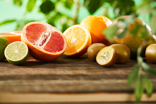 selective focus of kiwi, oranges, lime, grapefruit and mango on wooden table