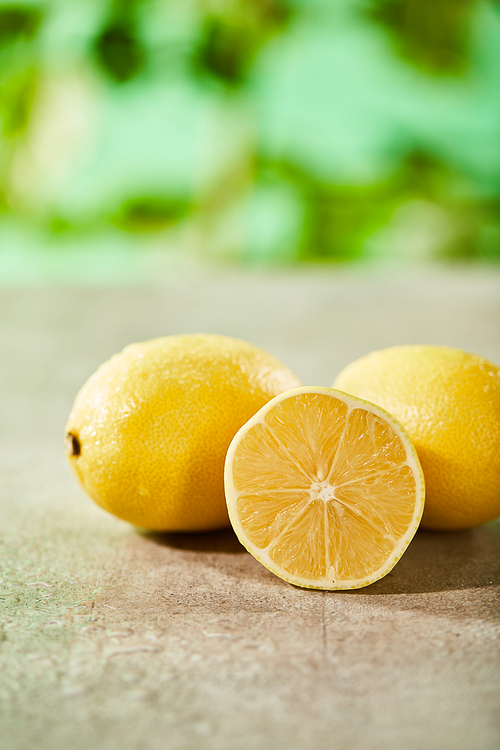 selective focus of whole and cut lemons with drops on marble surface