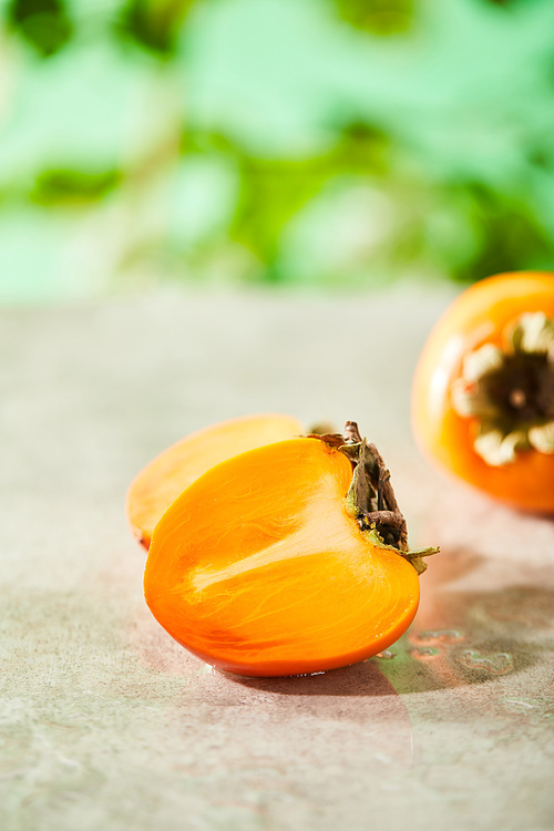 selective focus of whole and cut persimmons on marble surface