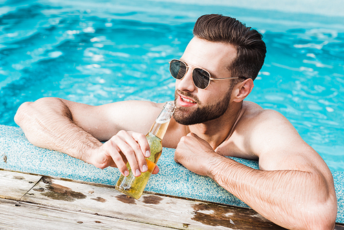 happy bearded man in sunglasses holding bottle with beer