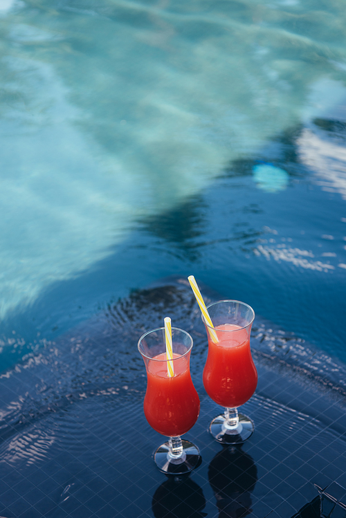two glasses with natural fruit refreshing beverage at poolside