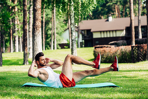 bearded sportsman working out on fitness mat in park