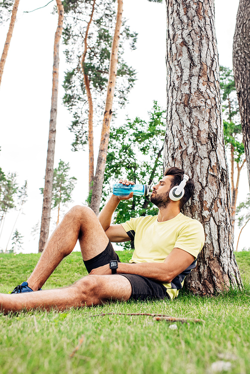 selective focus of man with closed eyes drinking water near trees