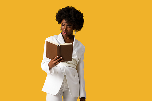 surprised african american woman reading book isolated on orange