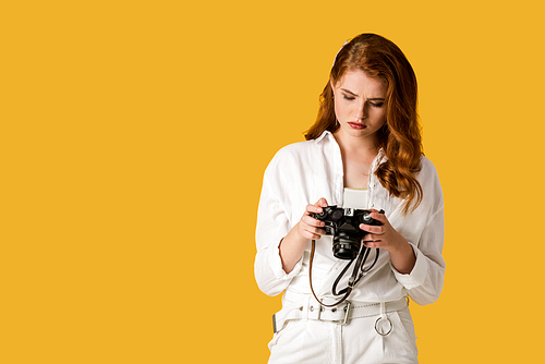 beautiful redhead girl holding digital camera isolated on orange