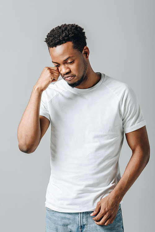 African American man in white T-short crying and looking down isolated on grey