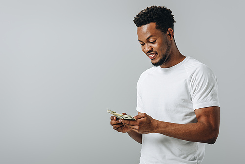 African American man counting dollar banknotes isolated on grey