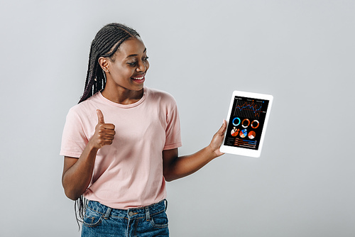 African American woman holding digital tablet with business charts and showing thumb up isolated on grey