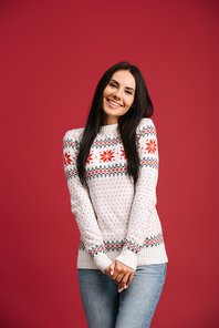 smiling woman posing in winter sweater isolated on red