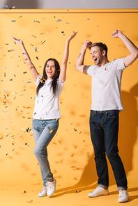 happy couple have fun on yellow with golden confetti