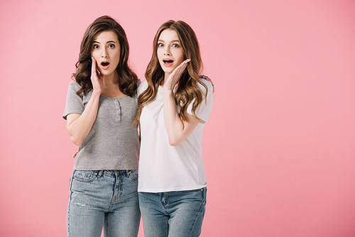 attractive and shocked women in t-shirts  isolated on pink