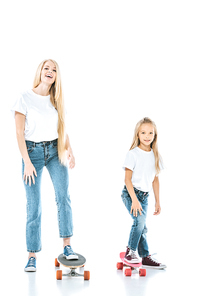 happy mother and daughter riding penny boards on white