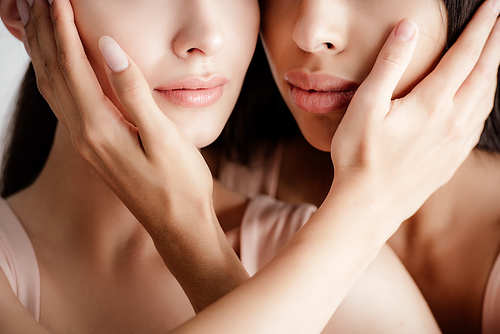 young multicultural girls in beige outfit tenderly touching each other faces