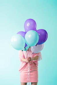 girl in pink outfit holding balloons in front of face isolated on turquoise