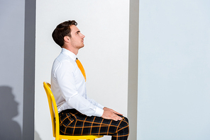 side view of man in plaid trousers sitting on white and grey