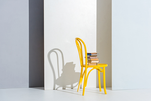 books on yellow chair on white and grey with copy space