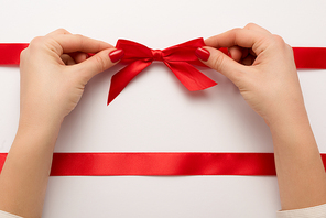 cropped view of woman touching red bow on white