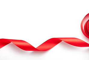 top view of curled and red ribbon on white with copy space