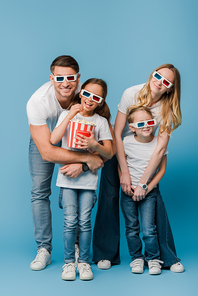 happy parents and children watching movie in 3d glasses and holding popcorn bucket on blue