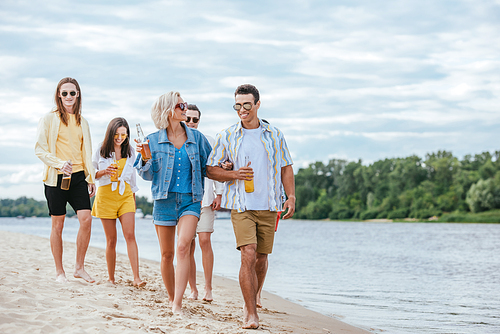 young interracial couple walking on riverside together with multiethnic friends