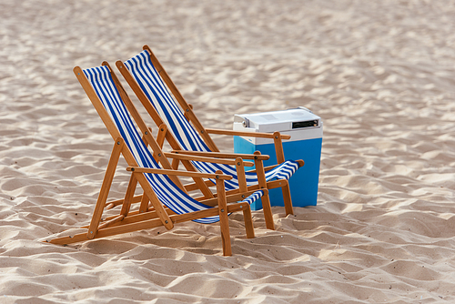 two chaise lounges and cooler box on sunny beach