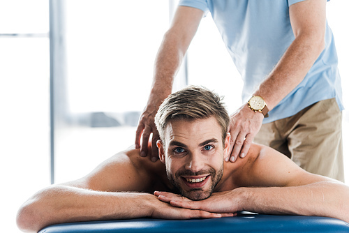 cropped view of chiropractor doing massage to positive patient on massage table