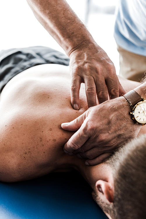 selective focus of chiropractor doing massage to shirtless patient