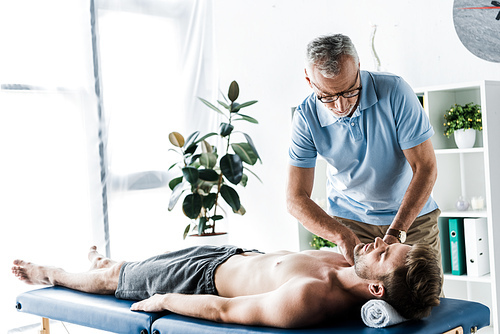 bearded chiropractor doing massage to handsome man on massage table