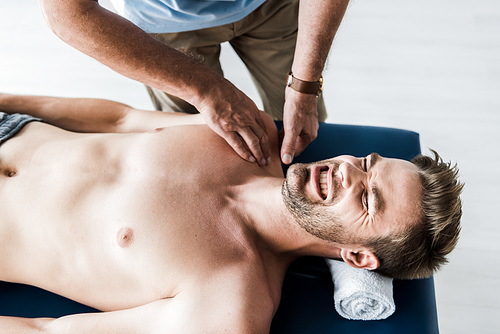 overhead view of chiropractor doing massage to man with pain