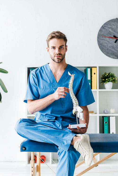 handsome doctor  while holding spine model in clinic