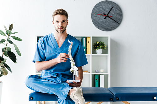 doctor  while holding spine model in clinic