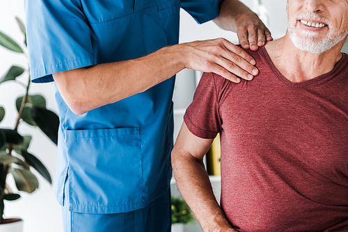 cropped view of doctor touching shoulder of bearded man