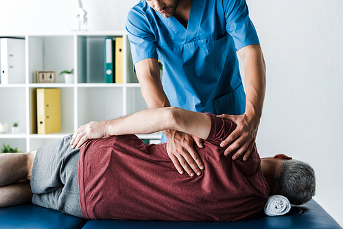 cropped view of doctor touching middle aged man lying on massage table