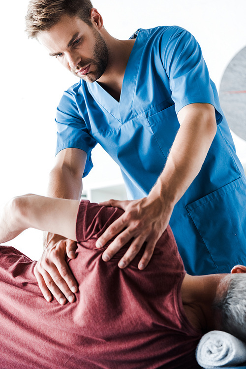 doctor touching mature man lying on massage table