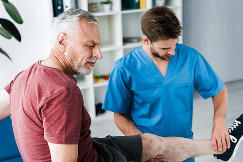 selective focus of bearded patient with closed eyes and pain near doctor