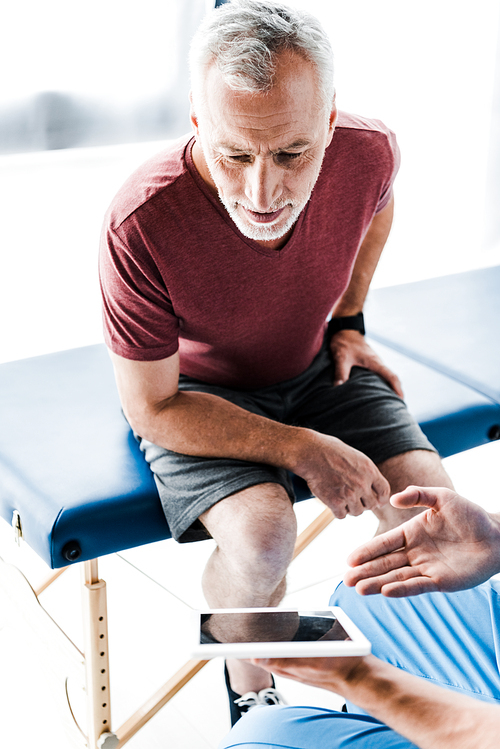 cropped view of doctor holding digital tablet and gesturing near mature patient