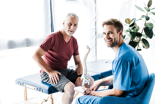 happy patient  near doctor holding spine model