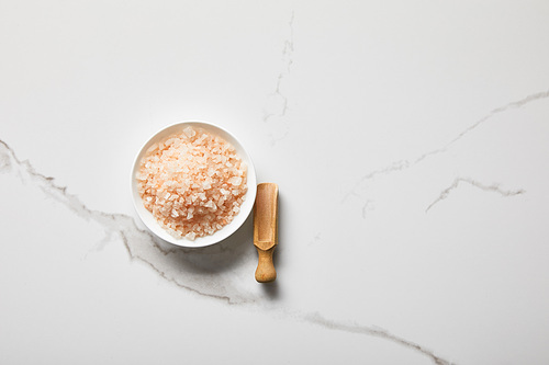 top view of 씨솔트 in bowl near wooden spatula on marble table