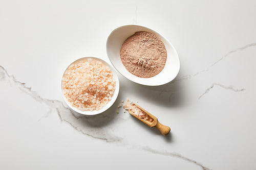 top view of clay powder and 씨솔트 in bowls on marble table near wooden spatula