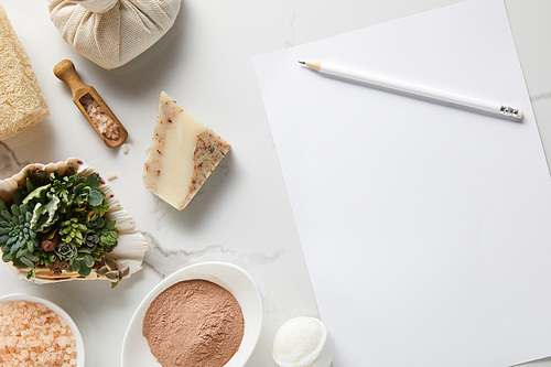 top view of organic cosmetics and white paper with pencil on marble table